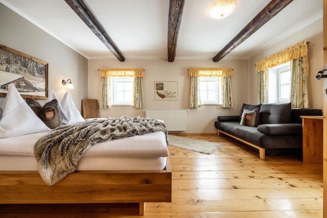 Schlafzimmer mit Doppelbett, Sofa, Vollholzparkettboden